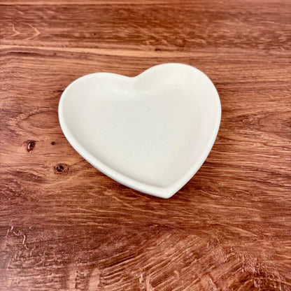 Heart-shaped trinket tray made from white jesmonite sat on a wooden surface